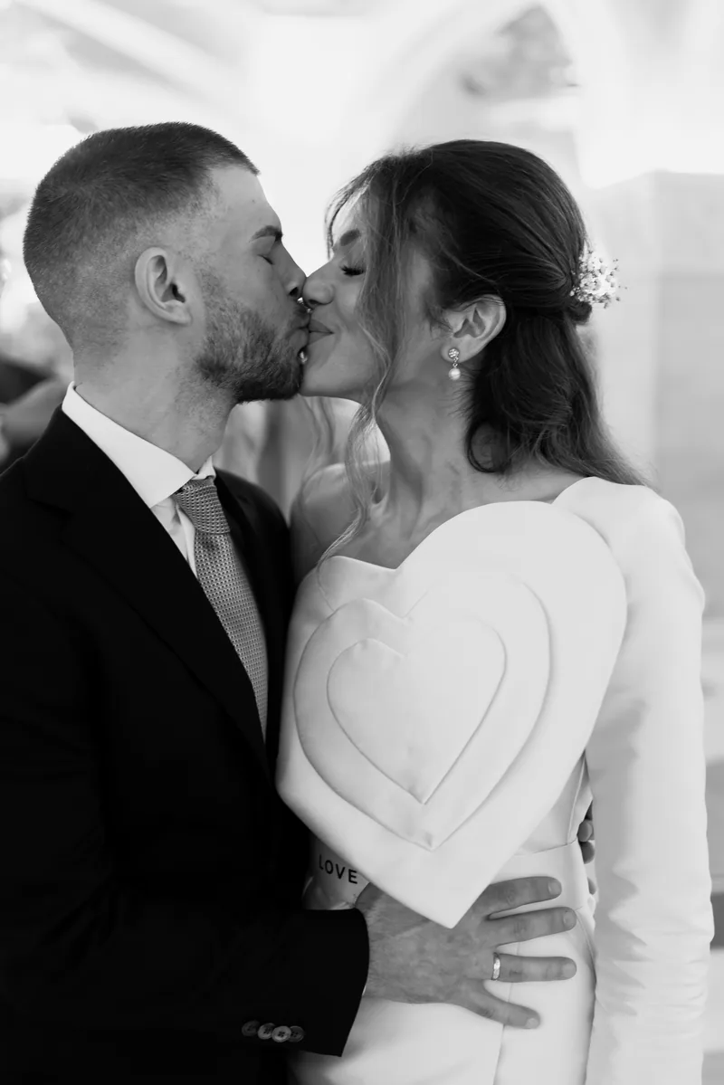 Intimate black and white kiss highlighting the bride's sculpted heart bodice dress.